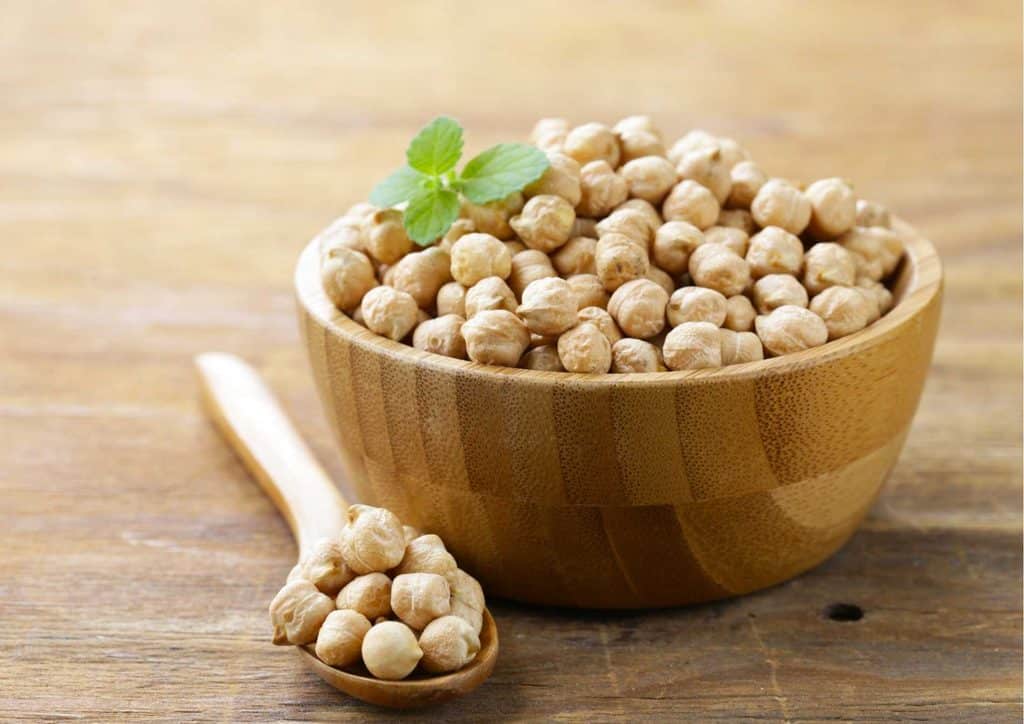 The Best Foods for Weight Loss 24 A wooden bowl filled with chickpeas placed on a rustic wooden table.