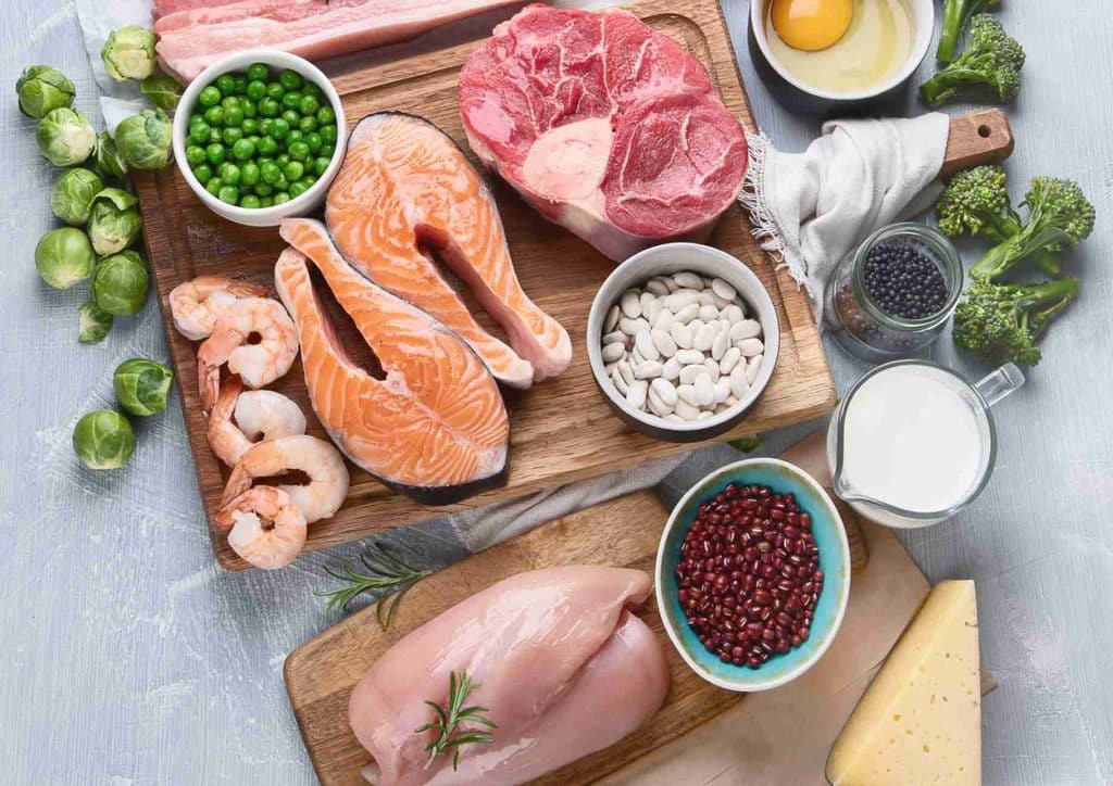 High-Protein Foods for Weight Loss 21 A cutting board displays an assortment of raw meat, fish, and fresh vegetables, ready for meal preparation.