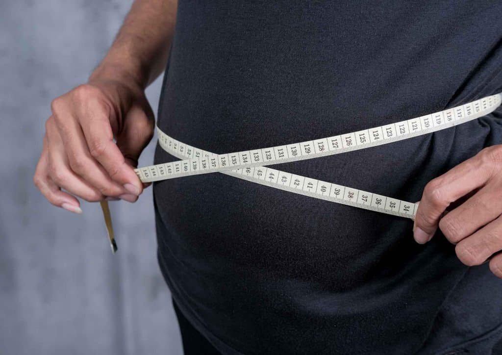 Is Pasta Good for Weight Loss? 21 A man measures his waist with a tape measure, focusing on his midsection for accurate sizing.