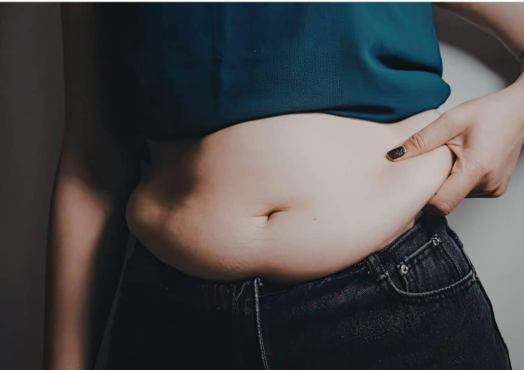 How to Lose Belly Fat: What a Nutritionist Recommends 26 A pregnant woman wearing a blue top, showcasing her large belly while standing outdoors.