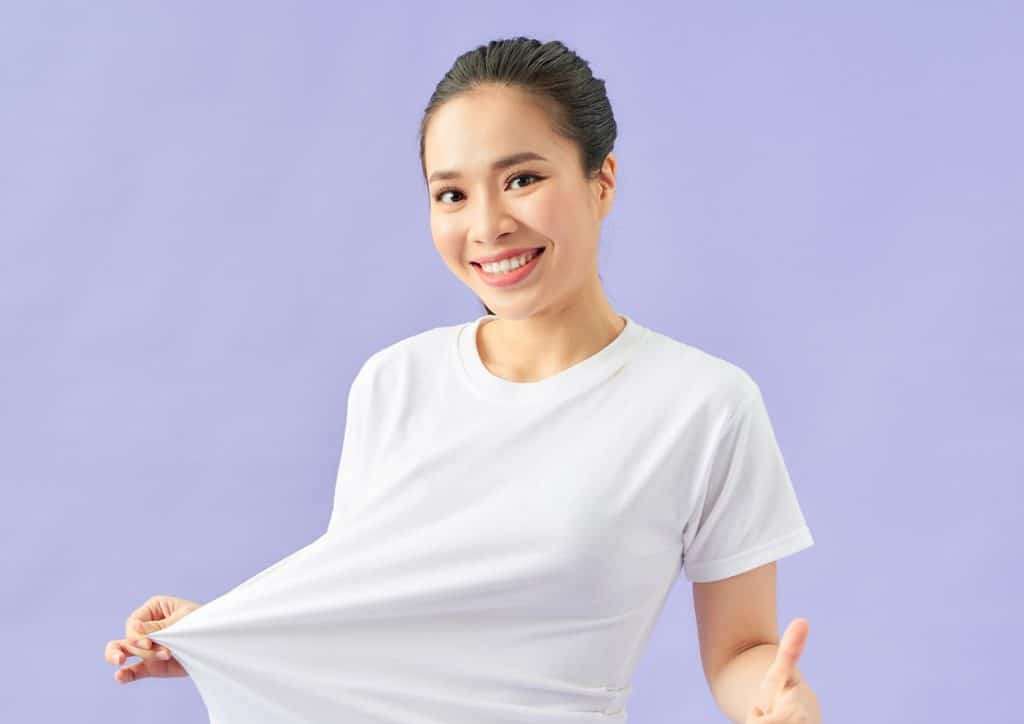 How to Lose Belly Fat: What a Nutritionist Recommends 24 An Asian woman wearing a white t-shirt, revealing her empty pocket, indicating financial emptiness or need.
