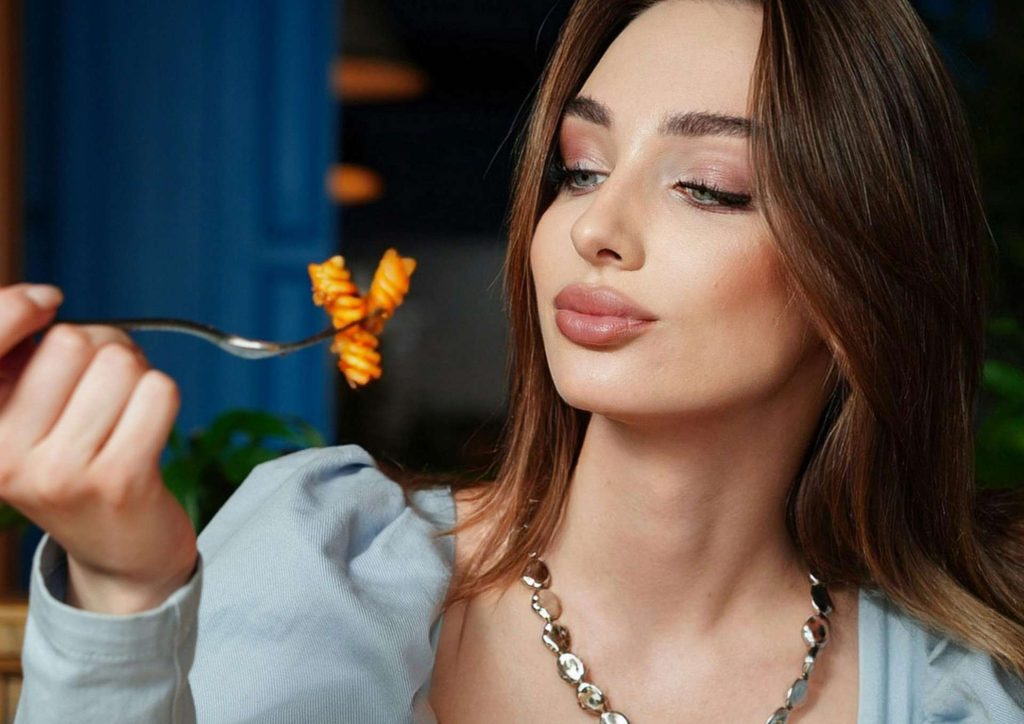 Is Pasta Good for Weight Loss? 27 A woman enjoying a plate of pasta, twirling it around her fork with a focused expression.