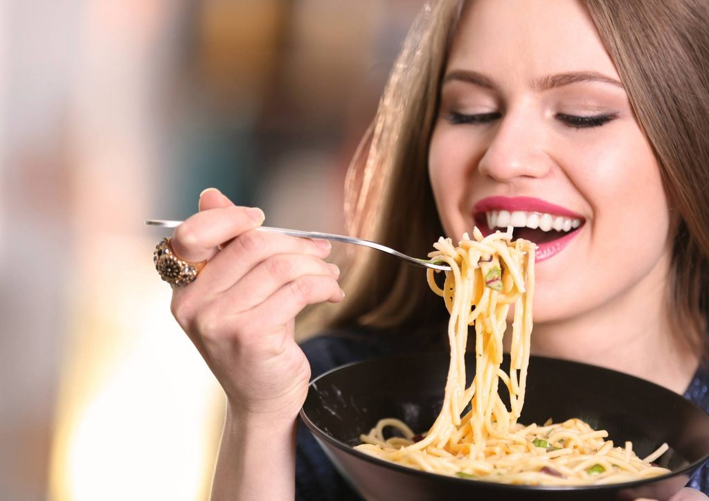 Is Pasta Good for Weight Loss? 4 A woman enjoying a plate of spaghetti, twirling noodles around her fork.