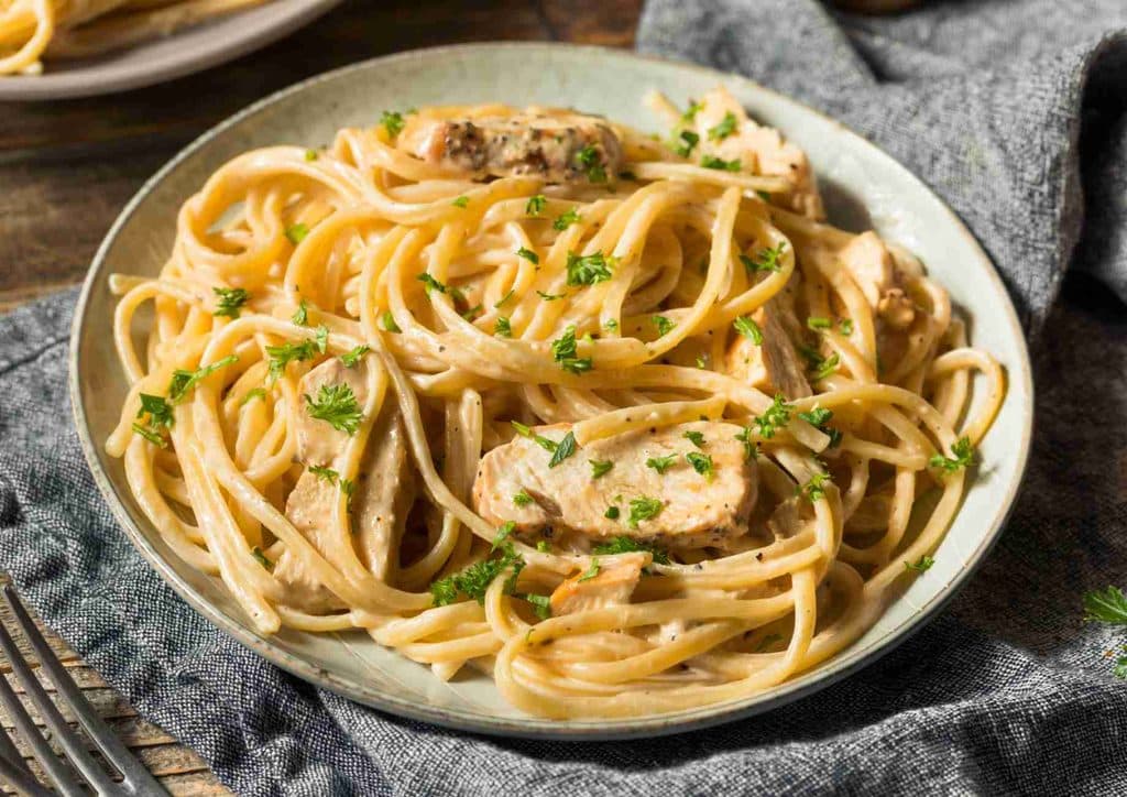 Is Pasta Good for Weight Loss? 8 A plate of chicken and pasta coated in a rich, creamy sauce garnished with herbs.