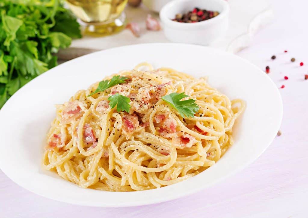 Is Pasta Good for Weight Loss? 11 Penne pasta topped with sautéed mushrooms and melted cheese, served in a white bowl.
