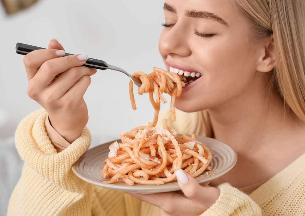 Is Pasta Good for Weight Loss? 16 A woman enjoying a plate of spaghetti, twirling noodles around her fork with a focused expression.