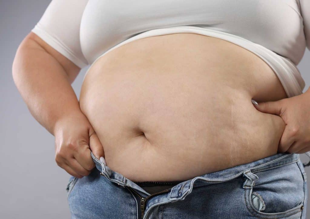 How to Lose Belly Fat: What a Nutritionist Recommends 6 A pregnant woman standing, showcasing her prominent belly with a serene expression on her face.