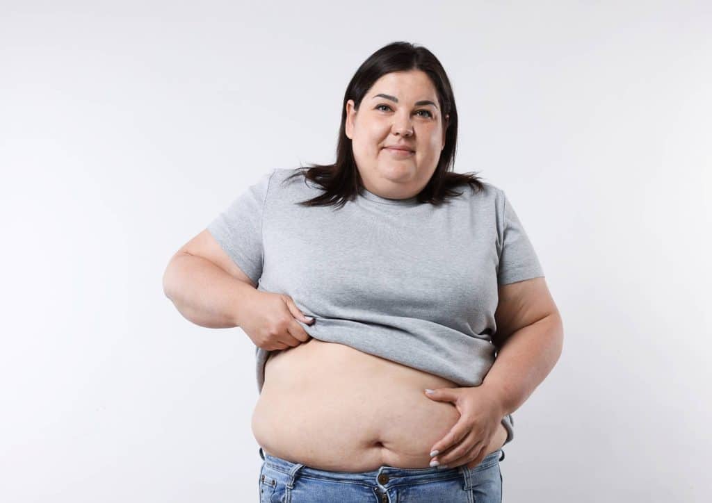 How to Lose Belly Fat: What a Nutritionist Recommends 20 A pregnant woman standing, showcasing her prominent belly with a serene expression on her face.