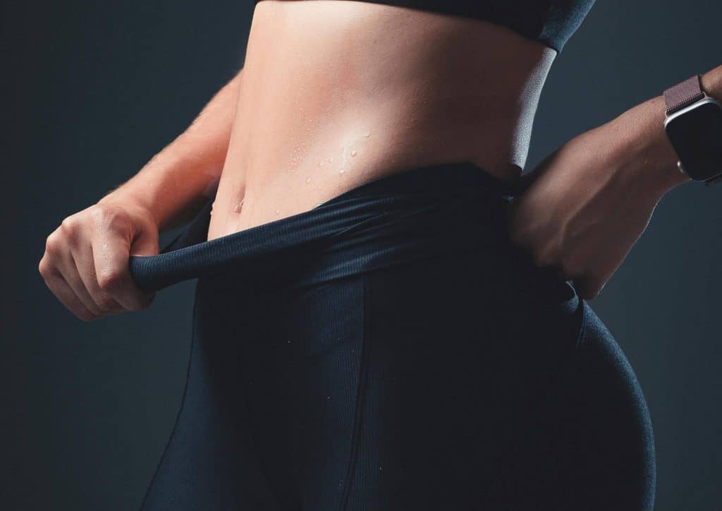 How to Lose Belly Fat: What a Nutritionist Recommends 25 A woman wearing black pants and a stylish watch, standing confidently with a neutral background.