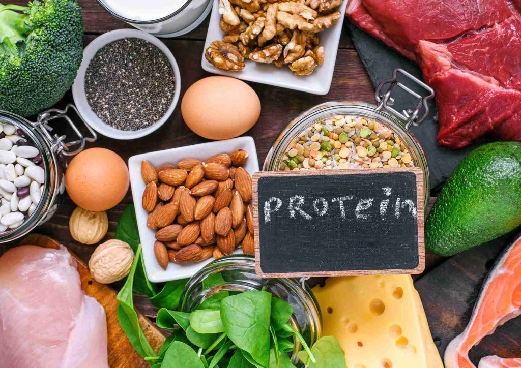 High-Protein Foods for Weight Loss 6 A variety of protein-rich foods including meat, beans, and nuts displayed on a wooden table.