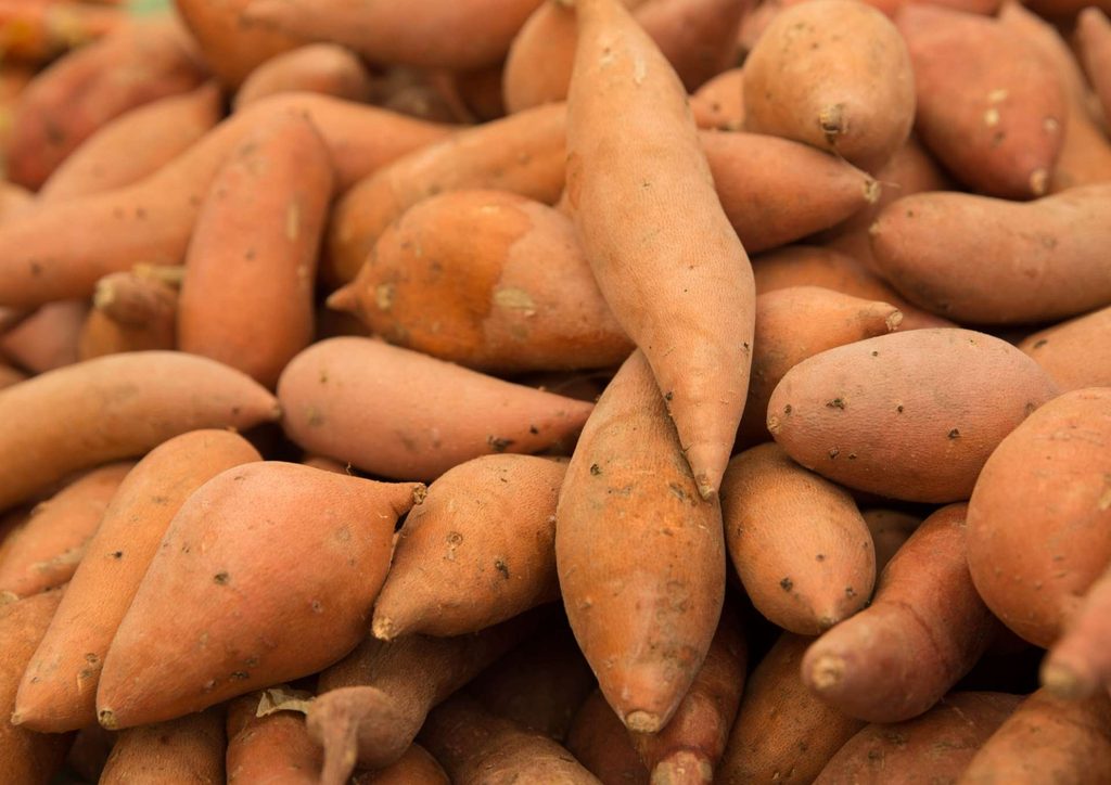 The Best Foods for Weight Loss 19 A close-up image of a pile of fresh, unpeeled sweet potatoes with earthy skin tones.