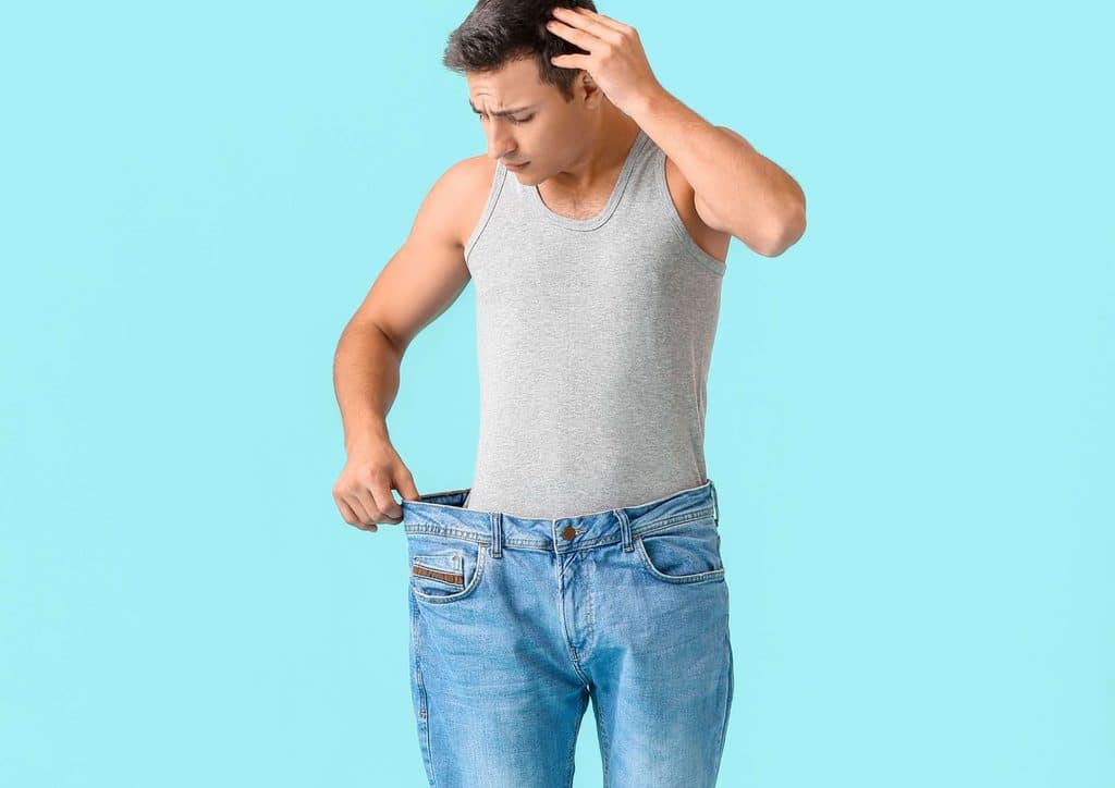 The Best Foods for Weight Loss 10 A man in jeans is holding up his pants with one hand, standing casually.