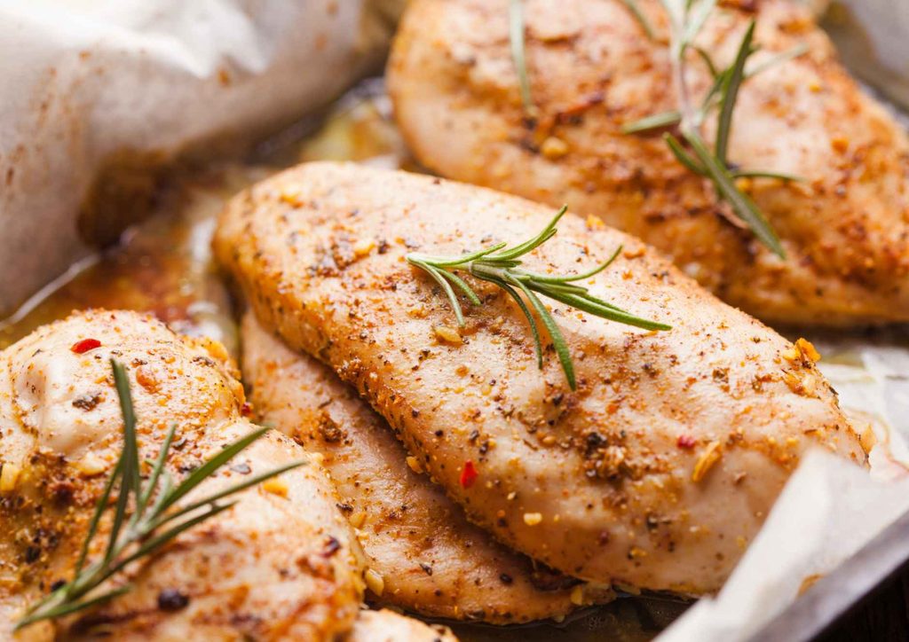 The Best Foods for Weight Loss 6 Baked chicken breasts garnished with fresh rosemary sprigs on a white plate.