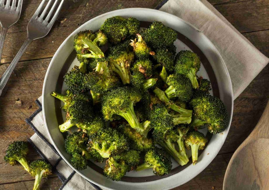 The Best Foods for Weight Loss 30 A plate of steamed broccoli accompanied by a fork and knife, ready for a meal.