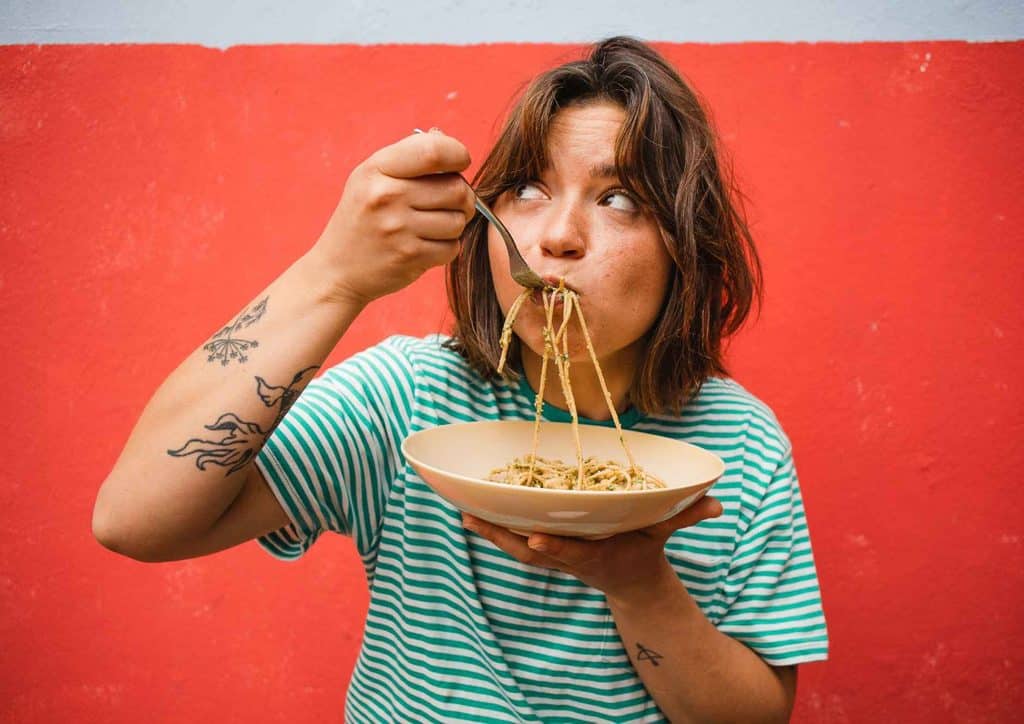 Is Pasta Good for Weight Loss? 24 A woman enjoying a plate of spaghetti, twirling noodles around her fork with a focused expression.