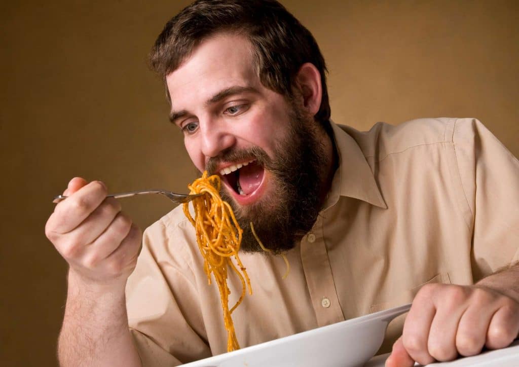 Is Pasta Good for Weight Loss? 5 A bearded man enjoying a plate of spaghetti, with a fork in hand, focused on his meal.