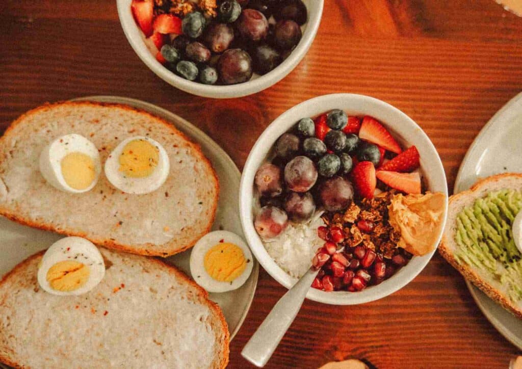 Nutritionist vs Clinical Nutritionist: What's the Difference? 2 A breakfast spread featuring bowls of eggs, fresh fruit, and slices of bread arranged on a table.