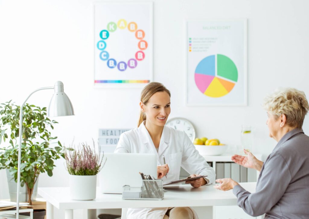 Clinical Nutritionist vs Nutritionist: What's the Difference 2 A woman and a doctor engage in a conversation in a medical office, discussing health-related matters.
