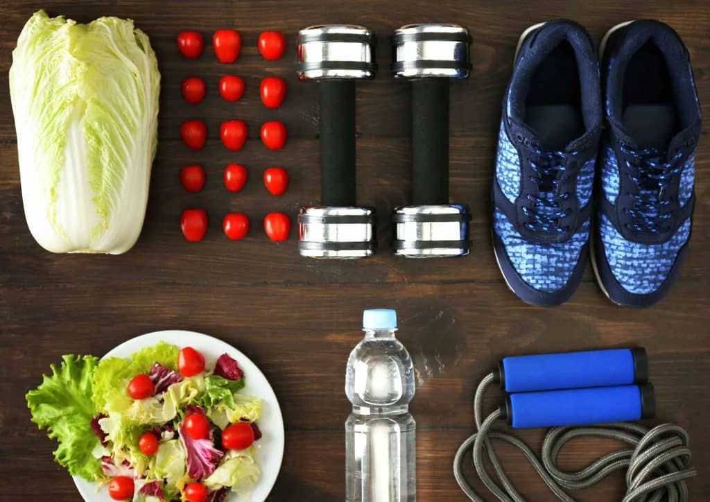 What Is a Sports Nutritionist? 11 A table set with a plate of vegetables and multiple bottles of water arranged neatly around it.