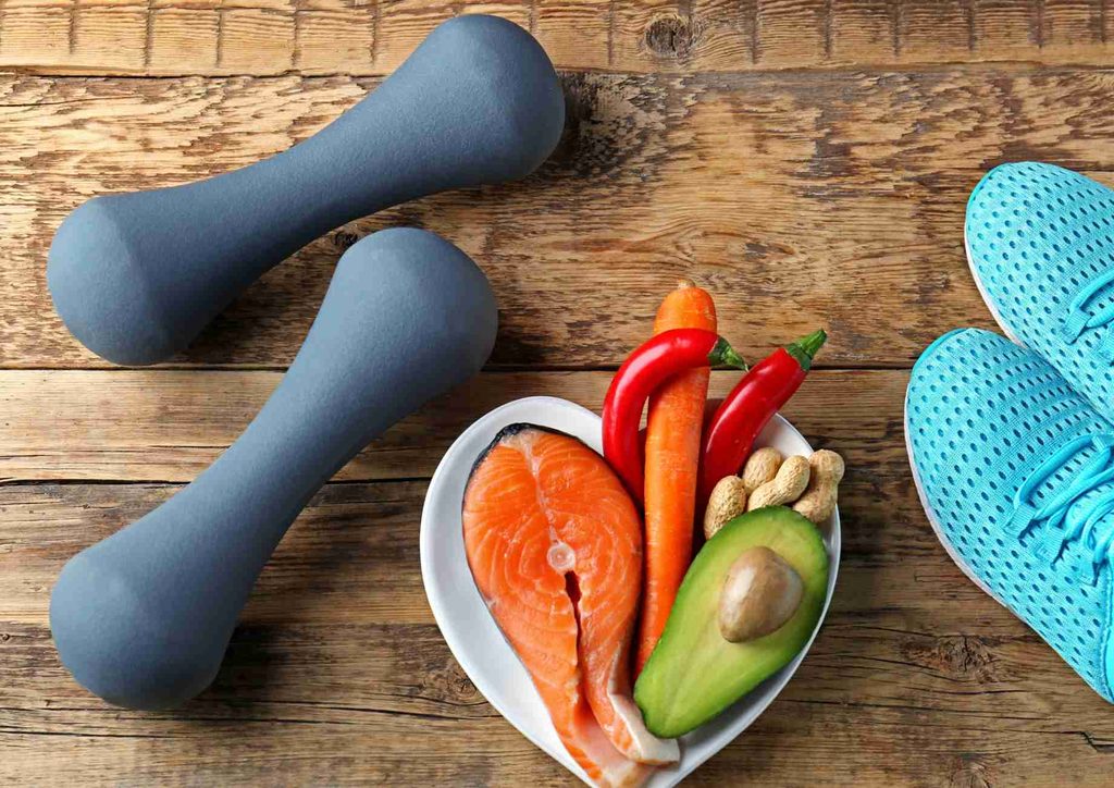 What Is a Sports Nutritionist? 23 A wooden table displays a plate of nutritious food next to dumbbells, representing a balanced approach to health and exercise.