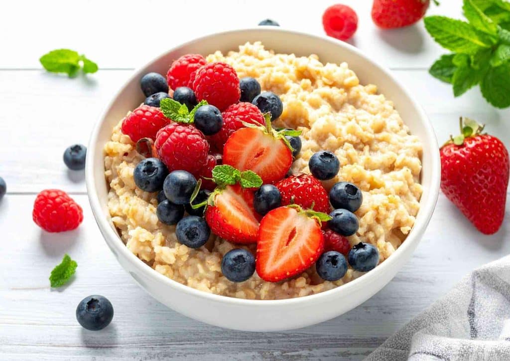 Are Oats Good for Weight Loss? 3 A bowl of oatmeal topped with fresh berries and a sprig of mint, showcasing a healthy breakfast option.