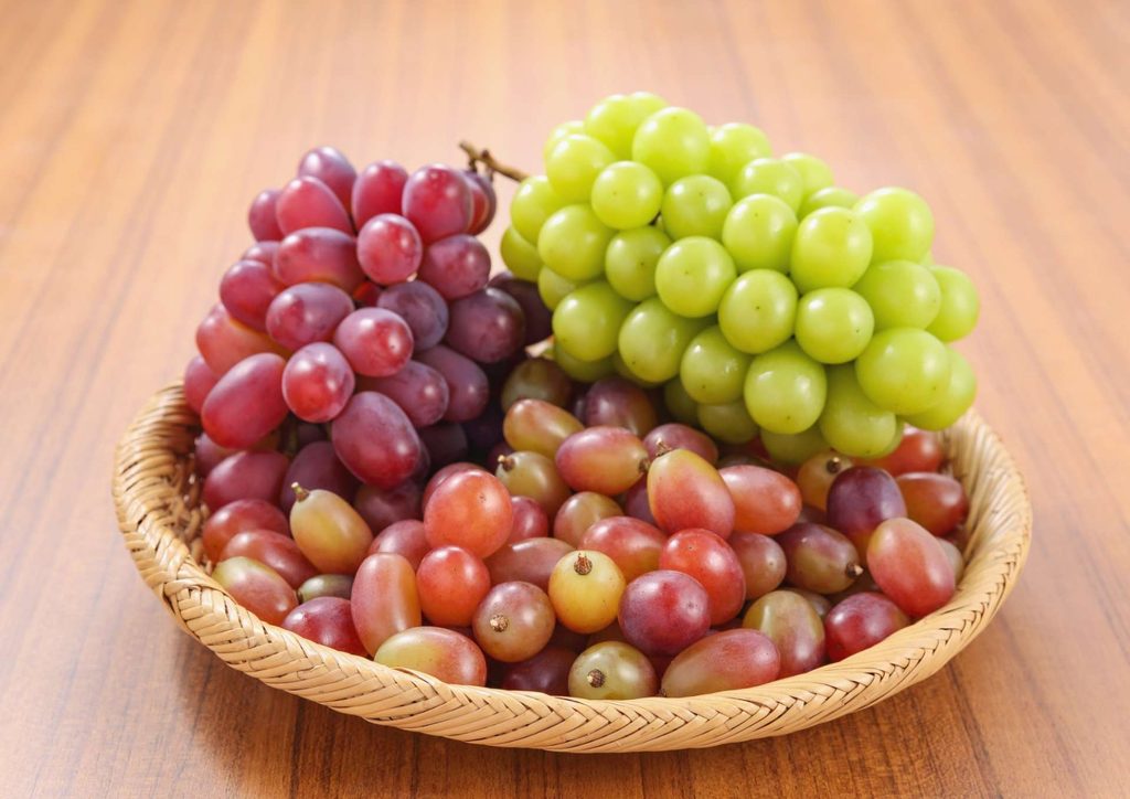Are Grapes Good for Weight Loss? 9 A basket filled with fresh grapes sits on a rustic wooden table.