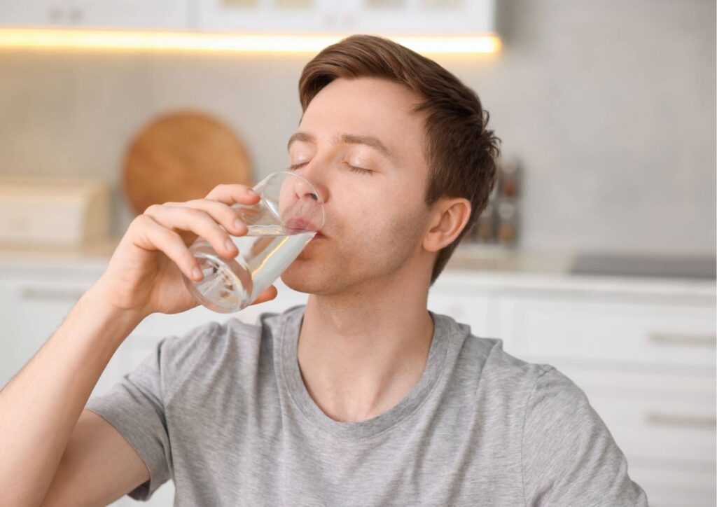 Is Coconut Water Good for Weight Loss? 8 A man holding a glass of water, tilting it towards his mouth to drink.