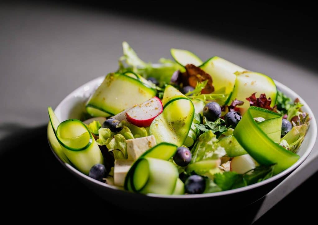 Natural Alternatives to Ozempic for Weight Loss 13 A bowl of colourful salad featuring cucumbers, blueberries, and various fresh vegetables.