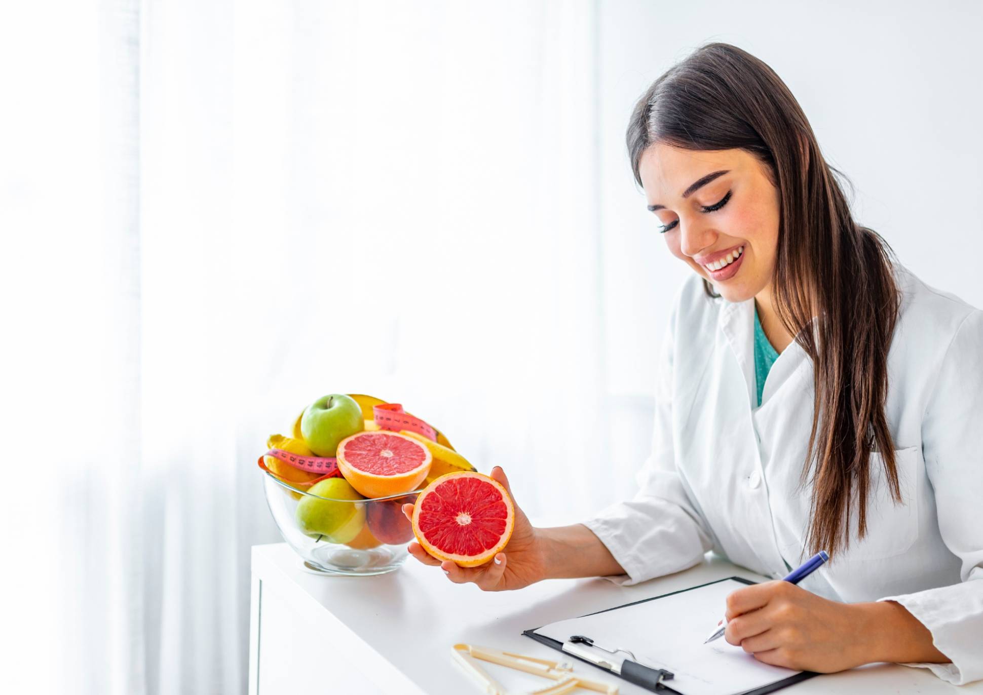 How to Choose the Best Weight Loss Nutritionist in Sydney 2 A woman in a white lab coat writes notes on a clipboard, focused on her task in a clinical setting.