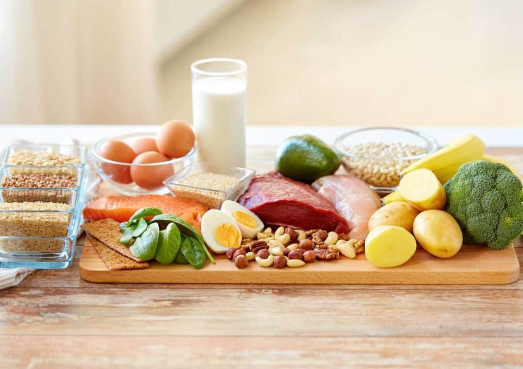 Why Am I Not Losing Weight? 8 Reasons a Nutritionist Sees Every Week 10 A wooden cutting board displaying an assortment of meat, eggs, fresh vegetables, and a carton of milk.