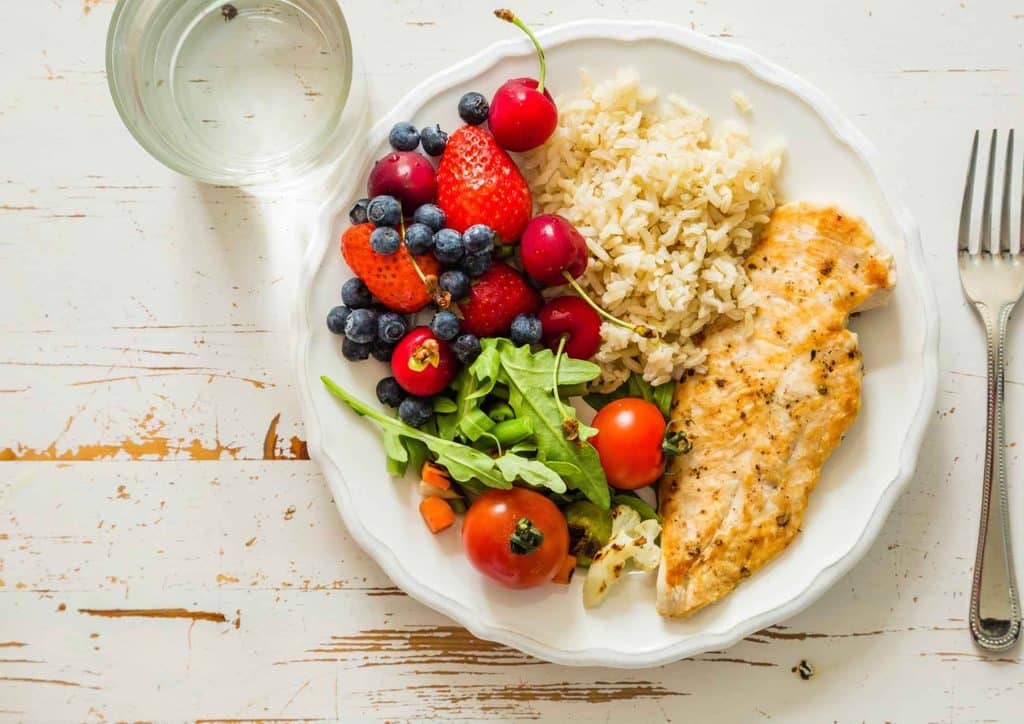 Not Losing Weight in a Calorie Deficit? Here's Why 21 A dish containing rice accompanied by fresh fruits and a selection of vibrant vegetables.