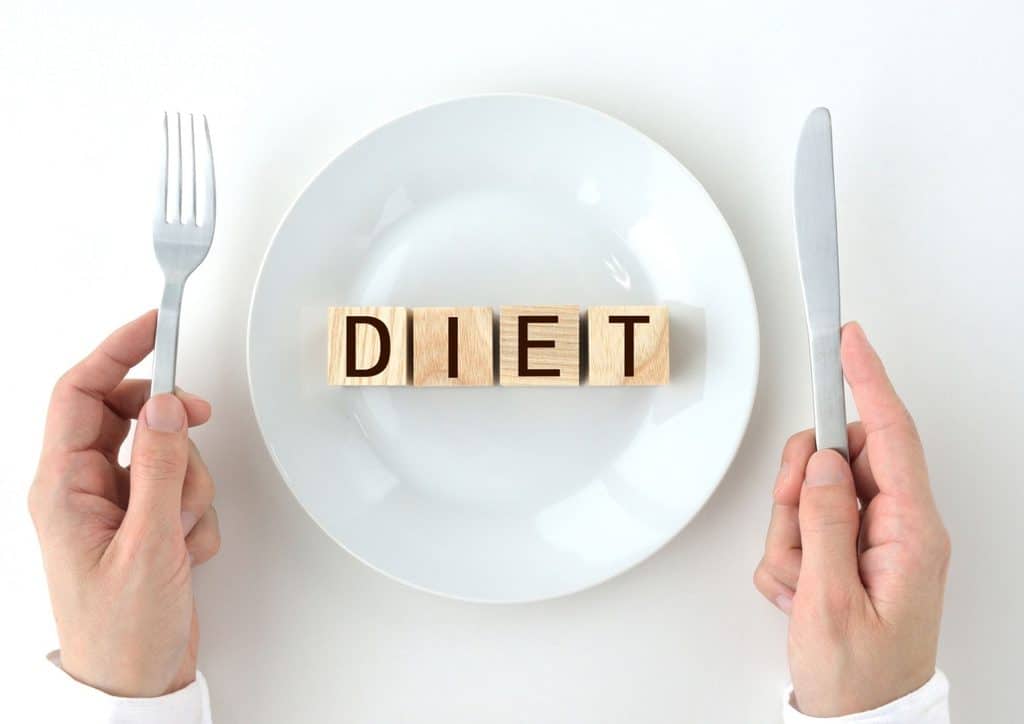 Why Am I Not Losing Weight? 8 Reasons a Nutritionist Sees Every Week 24 Wooden blocks spelling "diet" on a plate, accompanied by a fork and knife, symbolising healthy eating.