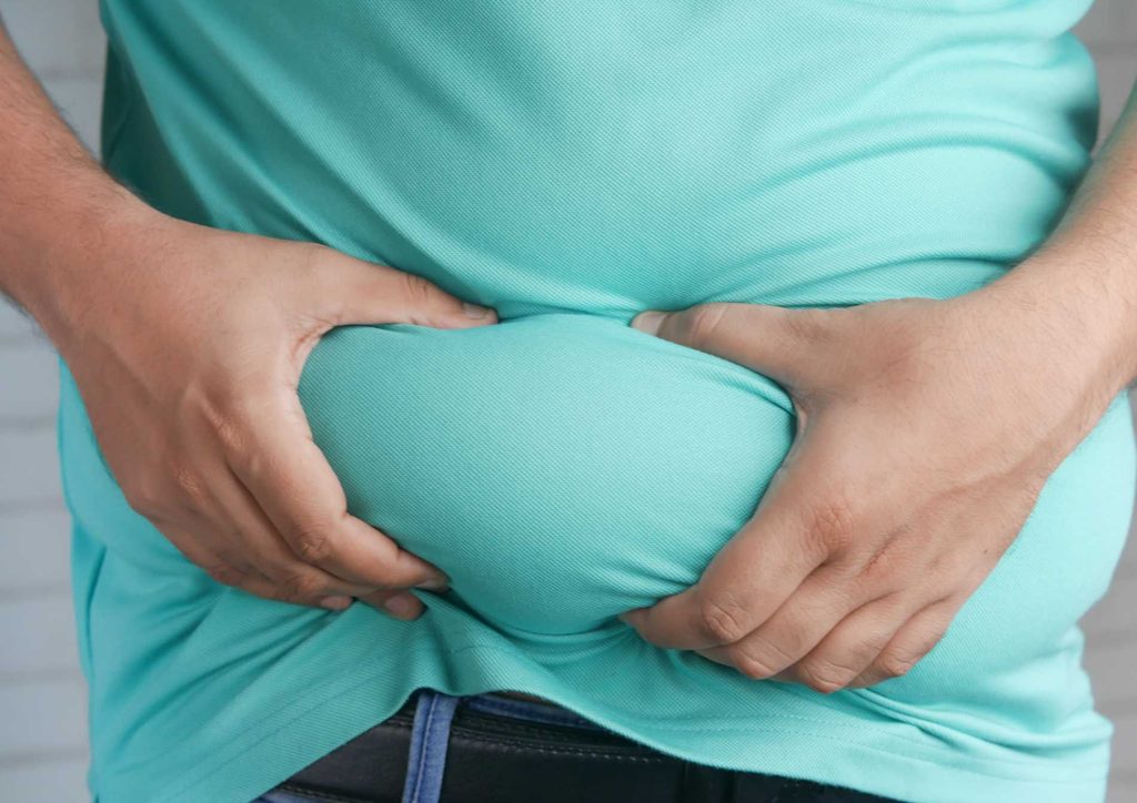 How to Choose the Best Weight Loss Nutritionist in Sydney 9 A man stands with his hands on his stomach, indicating discomfort or pain.