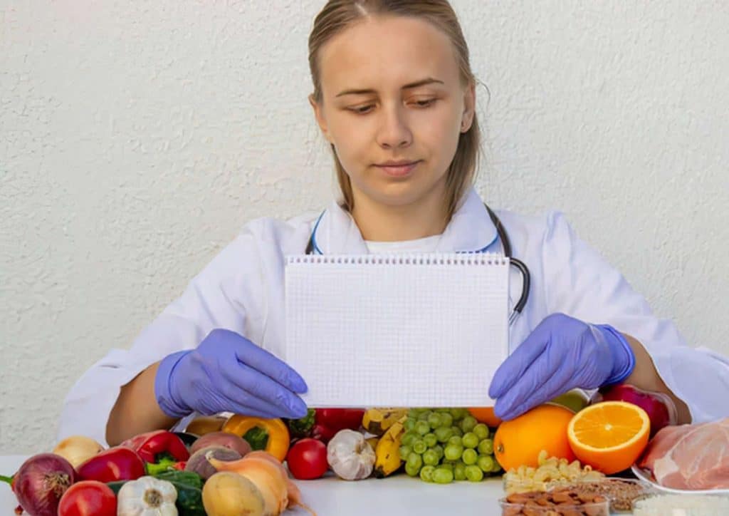 How to Choose the Best Weight Loss Nutritionist in Sydney 11 A cheerful woman in a lab coat presents a fresh apple, representing her focus on health and wellness.