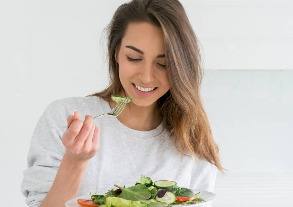How to Choose the Best Weight Loss Nutritionist in Sydney 19 A woman enjoying a fresh salad, using a fork to take a bite, seated at a table.