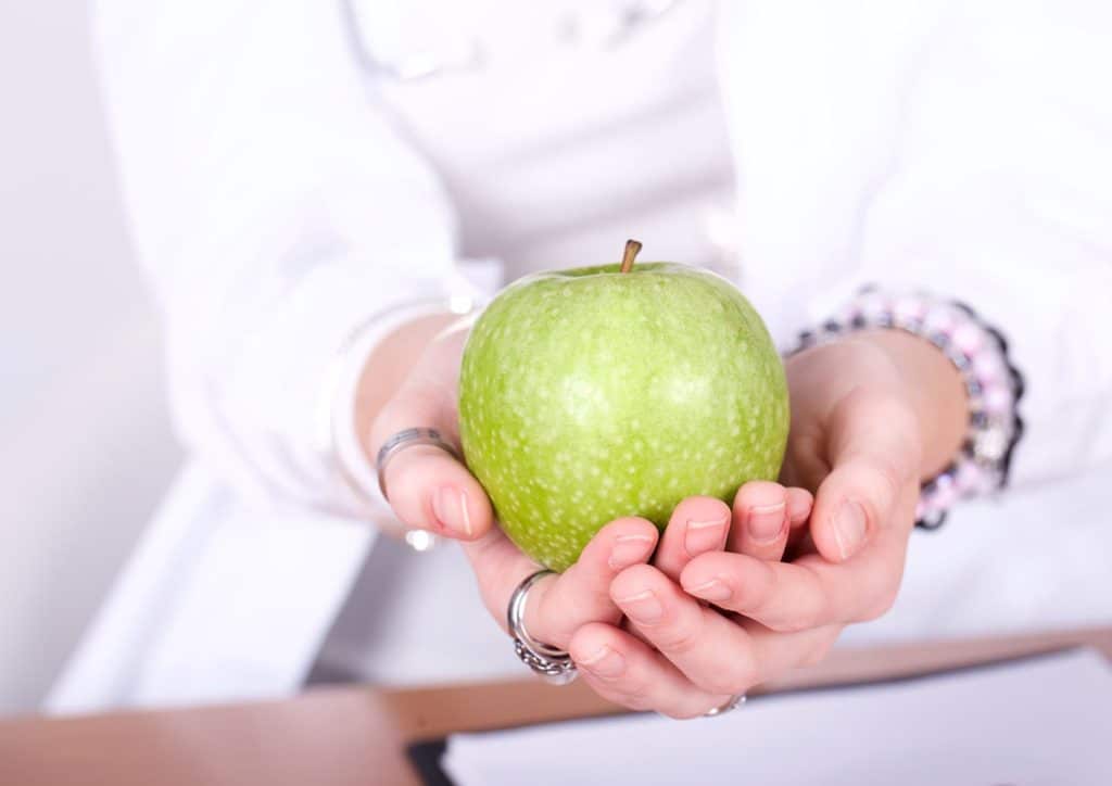 How to Choose the Best Weight Loss Nutritionist in Sydney 17 A person holding a red apple in both hands, showcasing its shiny surface and vibrant colour.