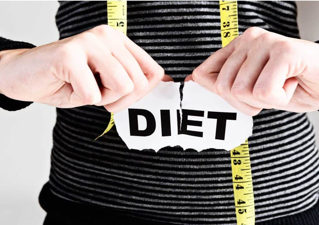 How to Lose Weight Fast (Safely, Without Crashing) 25 A woman holds a paper displaying the word "diet," symbolising her focus on health and nutrition.