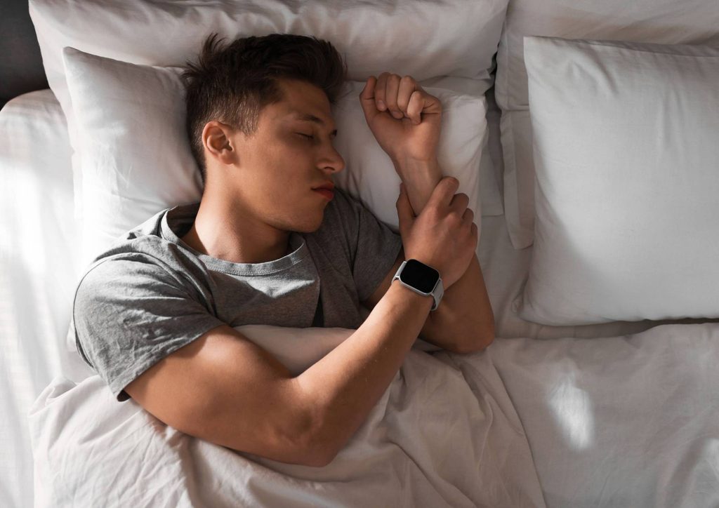 How to Lose Weight Fast (Safely, Without Crashing) 19 A man sleeping in bed with his arm resting on his wrist, appearing relaxed and peaceful.