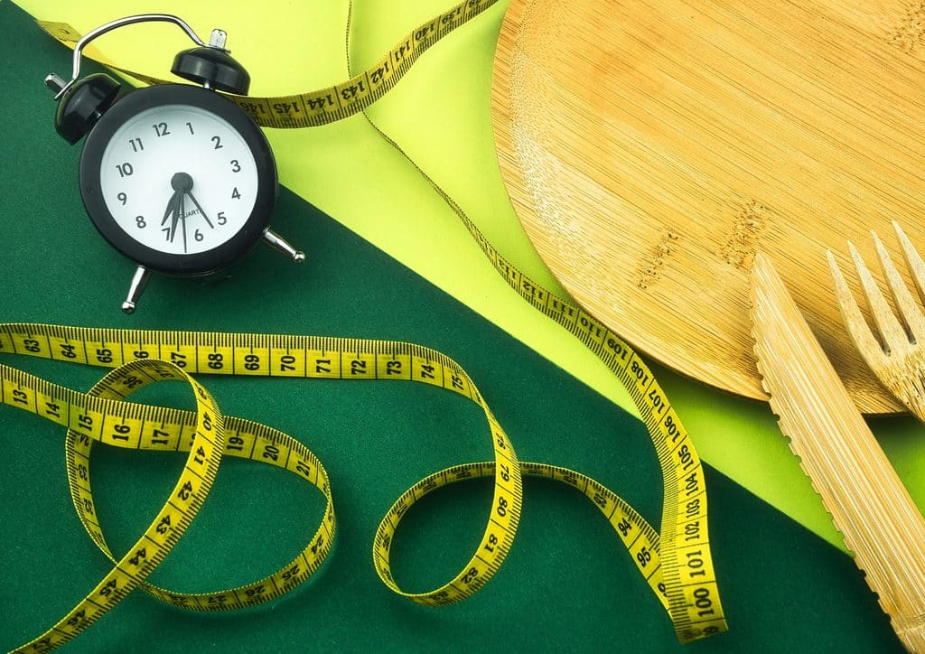 How to Lose Weight Fast (Safely, Without Crashing) 12 A plate with a fork and knife beside a measuring tape, symbolising portion control and healthy eating.