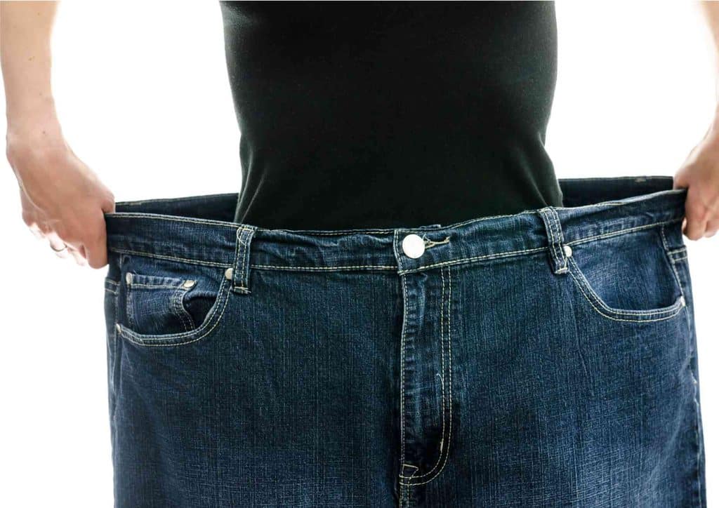How to Lose Weight Without Exercise 3 A person holding a pair of blue jeans, showcasing the fabric and style in a well-lit environment.