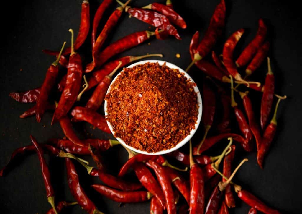 How to Speed Up Your Metabolism (What Actually Works) 18 A bowl filled with vibrant red chili powder set against a sleek black background.