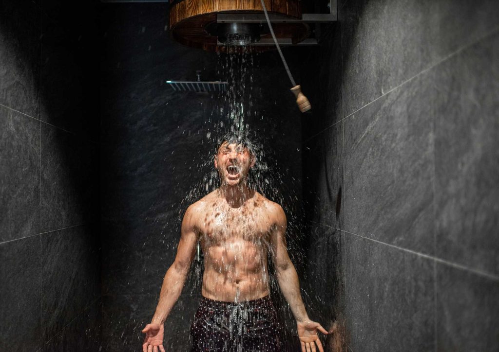How to Speed Up Your Metabolism (What Actually Works) 8 A man stands in a shower, water cascading over his head, creating a refreshing and invigorating atmosphere.