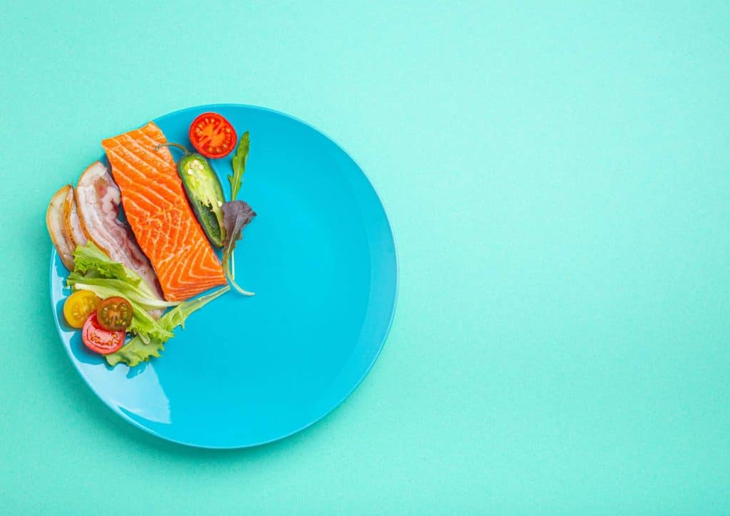 Intermittent Fasting for Weight Loss: Does It Actually Work? 24 A serving of salmon accompanied by a variety of vegetables and fresh tomatoes on a white plate.