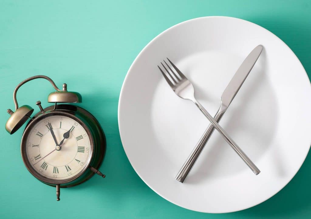 Intermittent Fasting for Weight Loss: Does It Actually Work? 12 A plate with a fork and knife arranged neatly on a turquoise background.