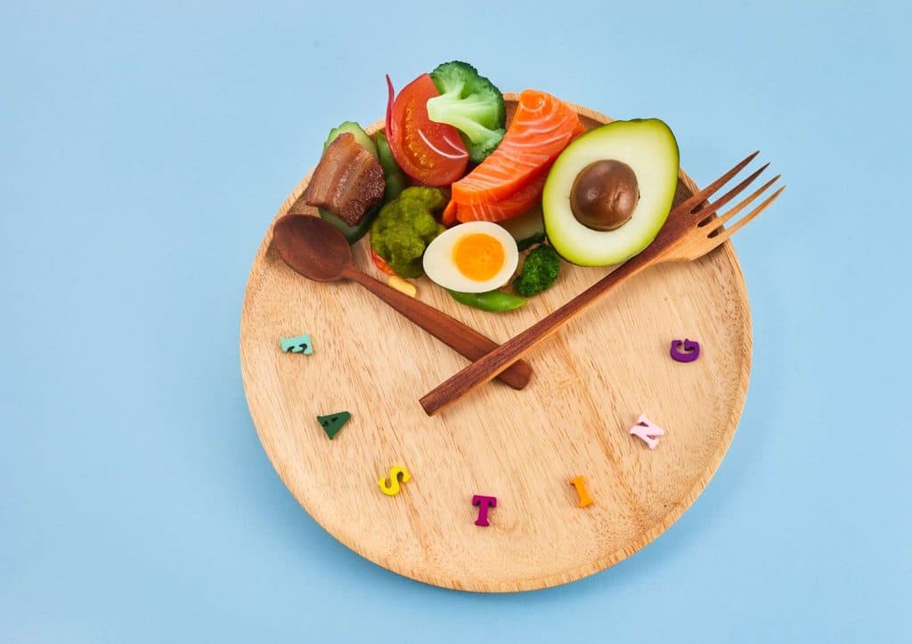 Intermittent Fasting for Weight Loss: Does It Actually Work? 9 A wooden plate displaying an assortment of food items alongside scattered letters.