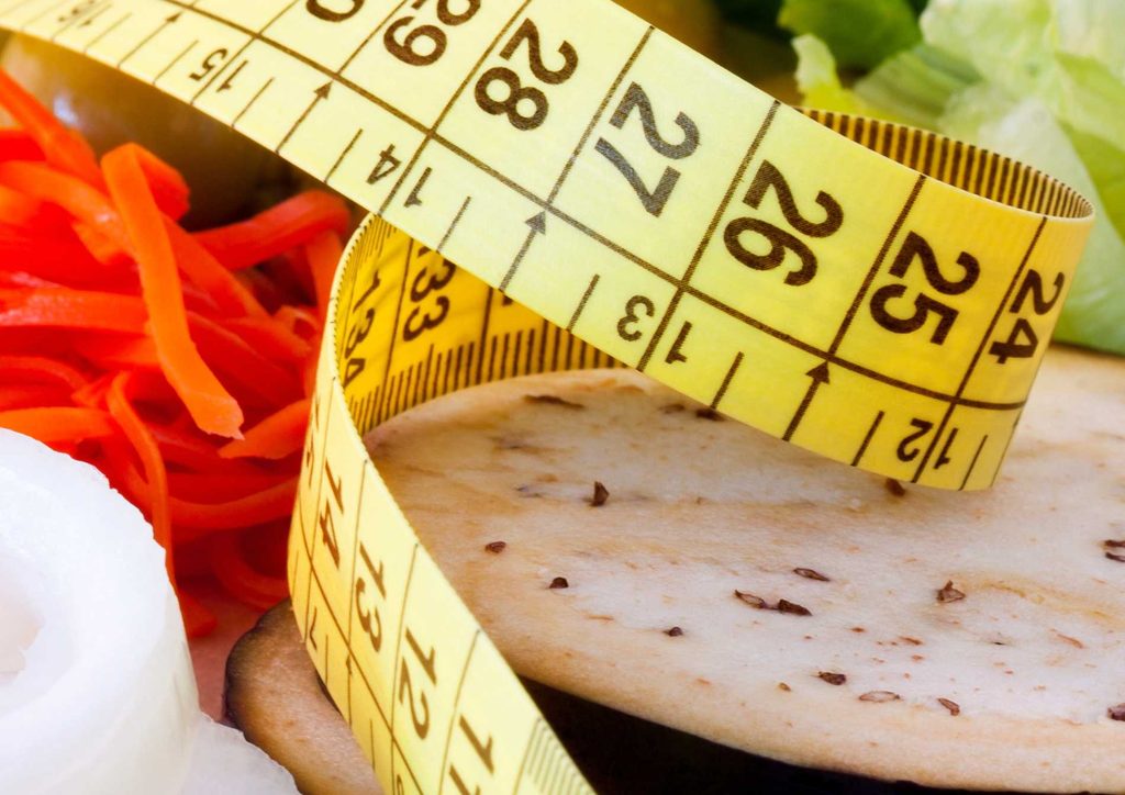 How to Lose Weight Without Exercise 20 A measuring tape is coiled around a plate of assorted vegetables, representing the relationship between diet and health.