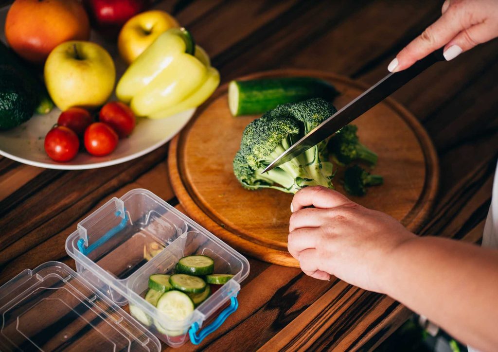 How to Speed Up Your Metabolism (What Actually Works) 28 A person skillfully chopping vegetables on a cutting board with a sharp knife in a well-lit kitchen.