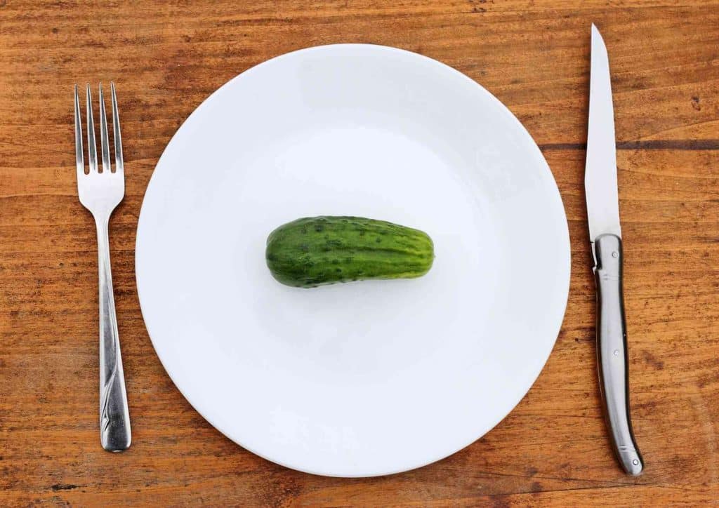 How to Speed Up Your Metabolism (What Actually Works) 21 A plate featuring a sliced cucumber, accompanied by a knife and fork on the side.