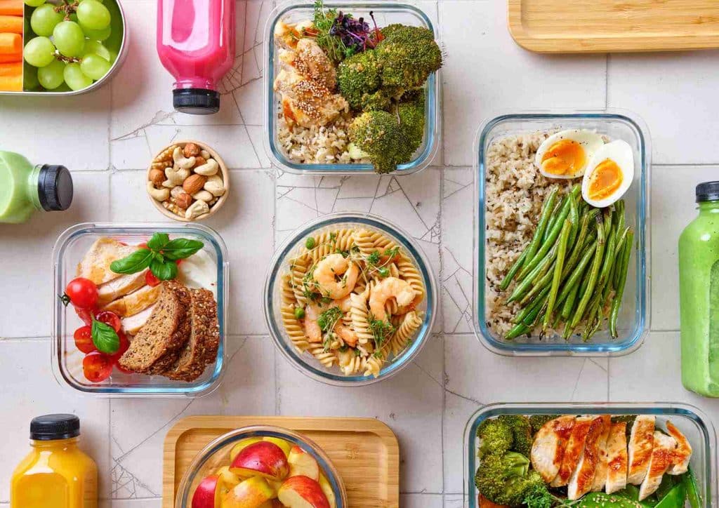 How to Speed Up Your Metabolism (What Actually Works) 12 Assorted nutritious meals displayed in plastic containers, featuring vibrant ingredients like greens, grains, and lean proteins.