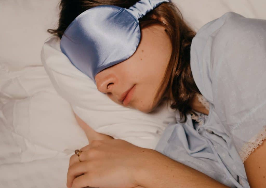 Natural Alternatives to Ozempic for Weight Loss 18 A woman peacefully sleeping while wearing a blue eye mask to block out light.